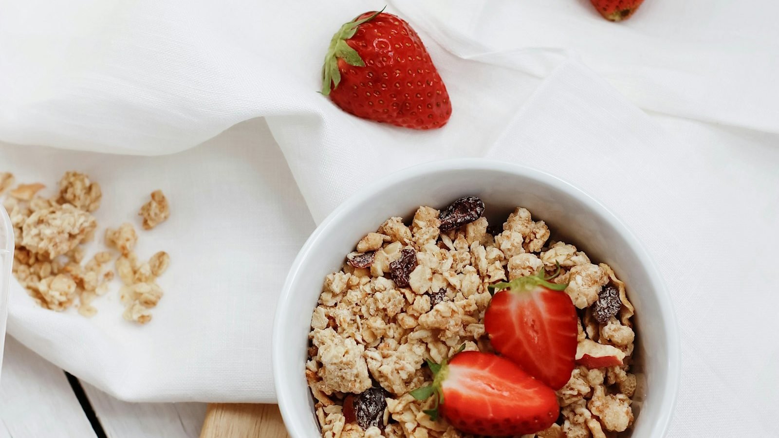 A bowl of granola topped with fresh strawberries