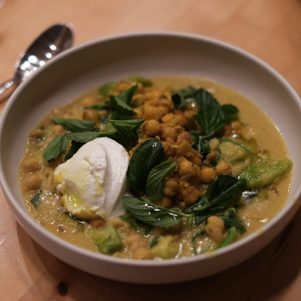 Bowl of chickpea curry with spinach leaves and a dollop of yogurt