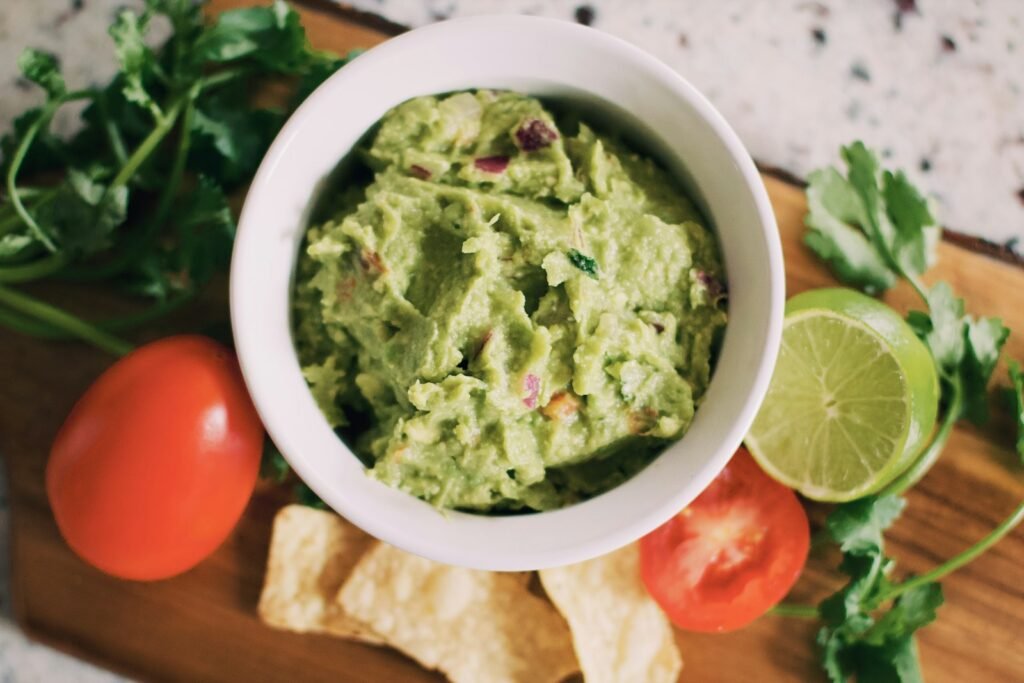 Bowl of chunky guacamole with tomatoes, lime and tortilla chips