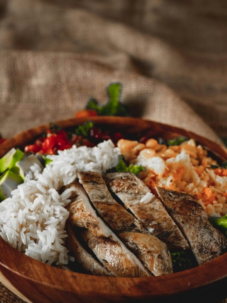 Sliced grilled chicken breast served with rice and vegetables